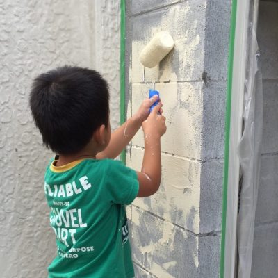 ローラーで外壁塗装を体験しているお子様